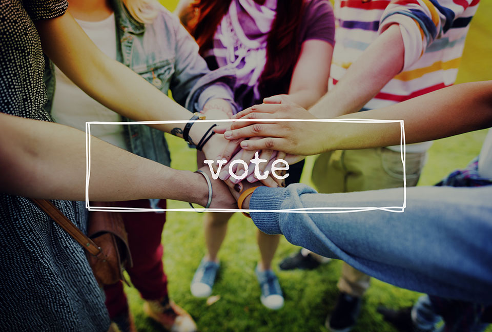 The word "vote' in a letterbox set against a picture of youth forming a circle and joining hands